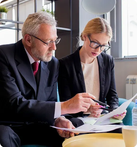 Two business professionals reviewing documents together in an office setting.