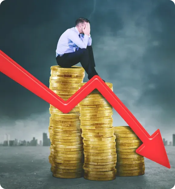 A distressed man in business attire sitting on stacks of gold coins with a large red downward arrow over the coins, symbolizing financial loss.
