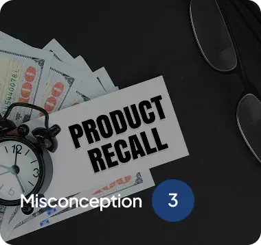 Table with hundred-dollar bills, an alarm clock, eyeglasses, and a card labeled 'Product Recall' on a dark surface.
