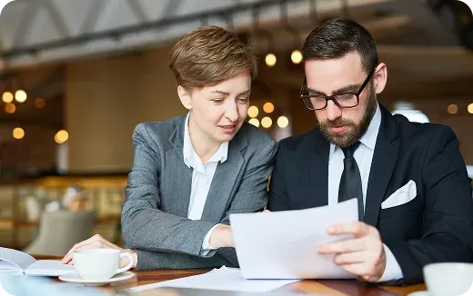 Two business professionals in a cafe reviewing documents together.
